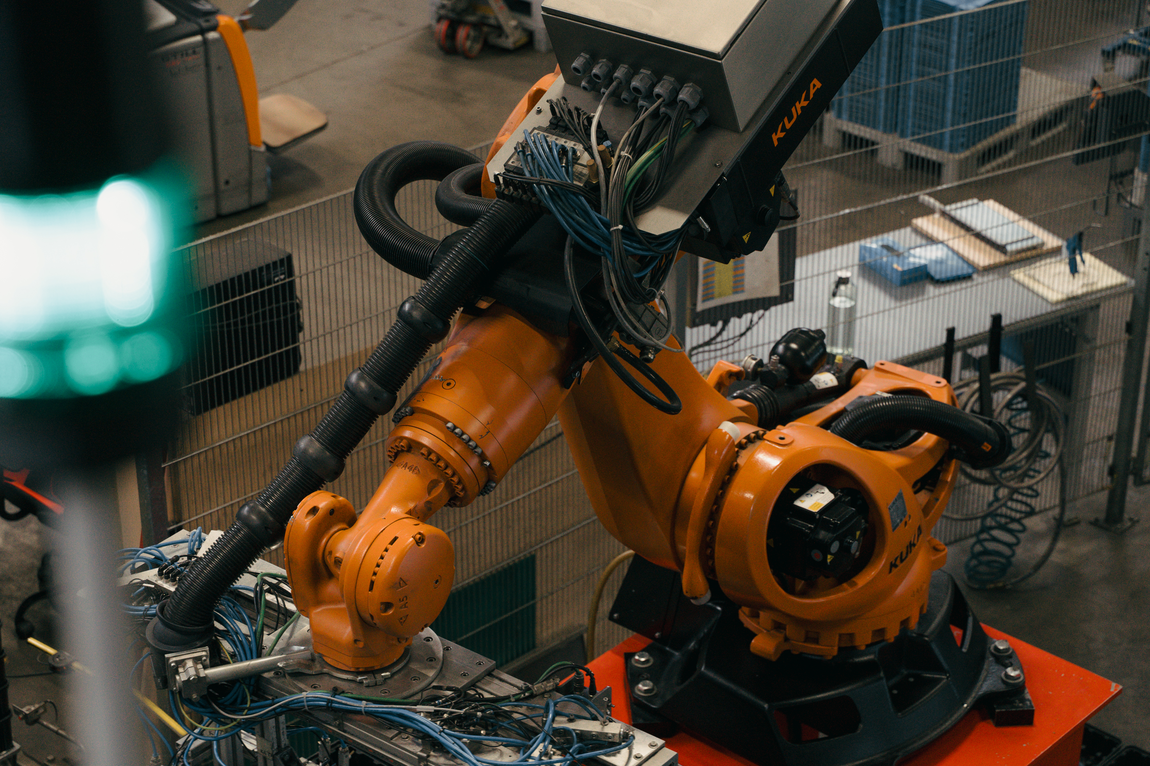 Industrieroboterarm von KUKA mit vielen Kabeln und Greifvorrichtung.