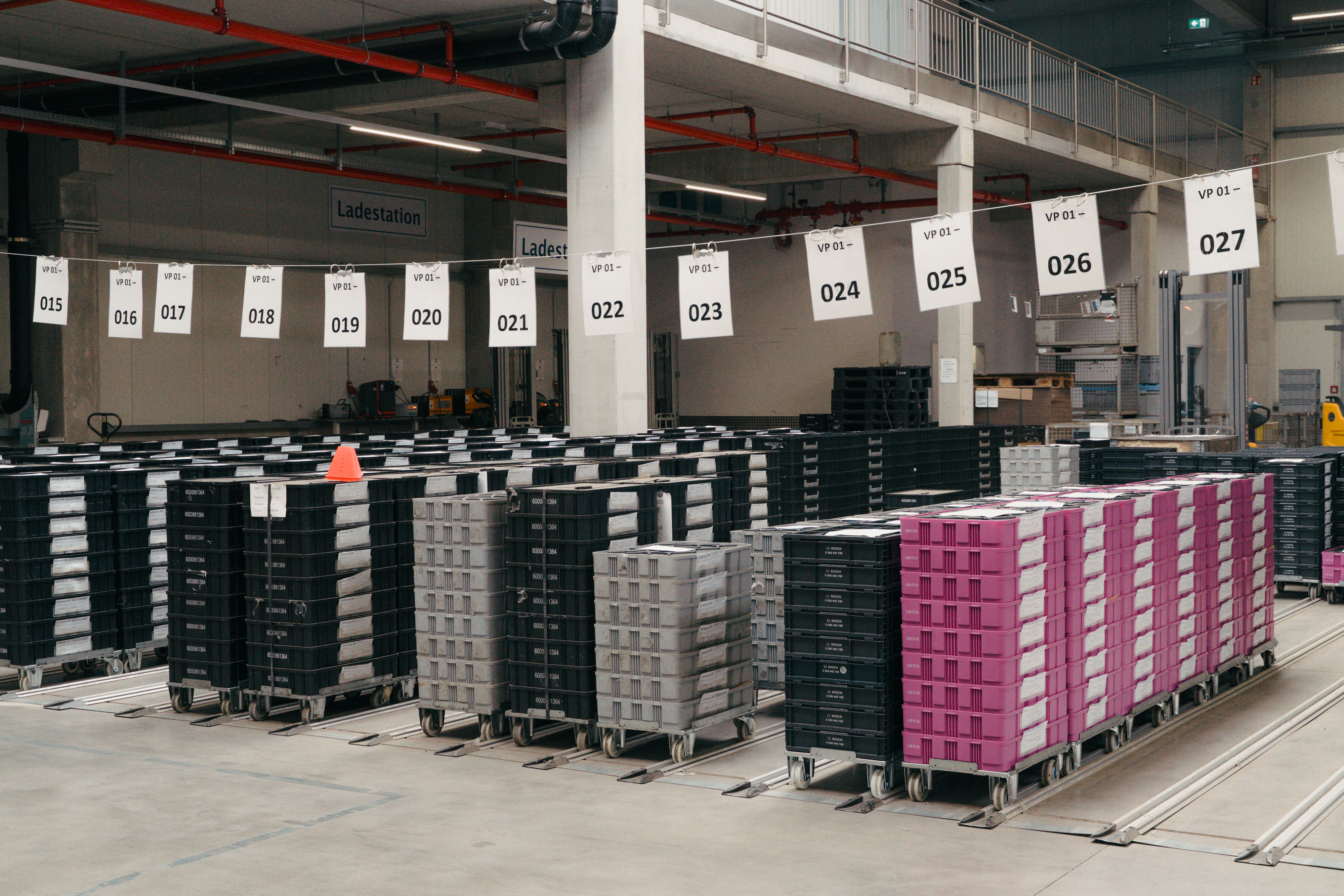 Beschriftete Lagerplätze mit gestapelten Transportboxen auf Rollen.