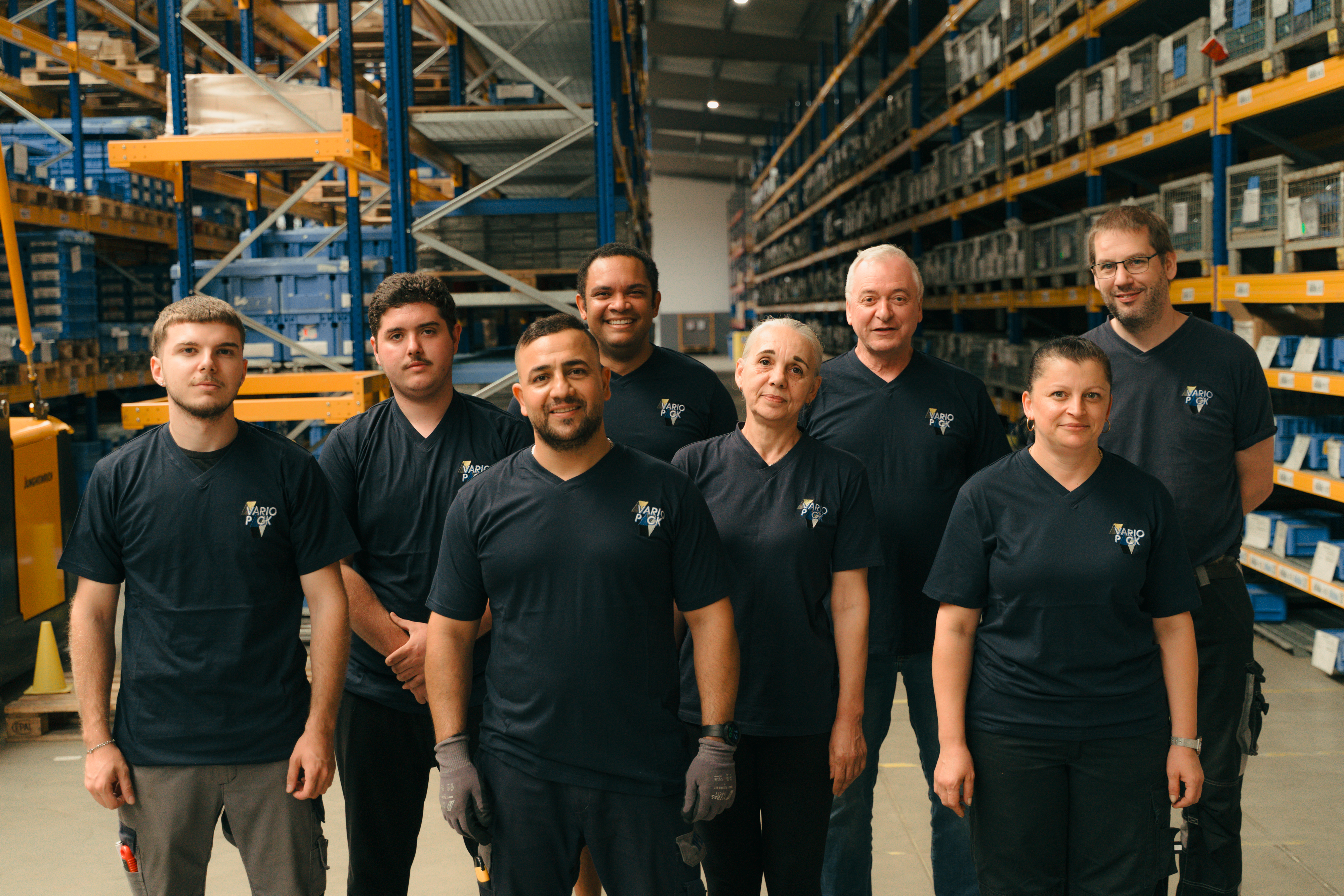 Teamfoto von Mitarbeitenden in schwarzer Variopack-Kleidung im Lager.