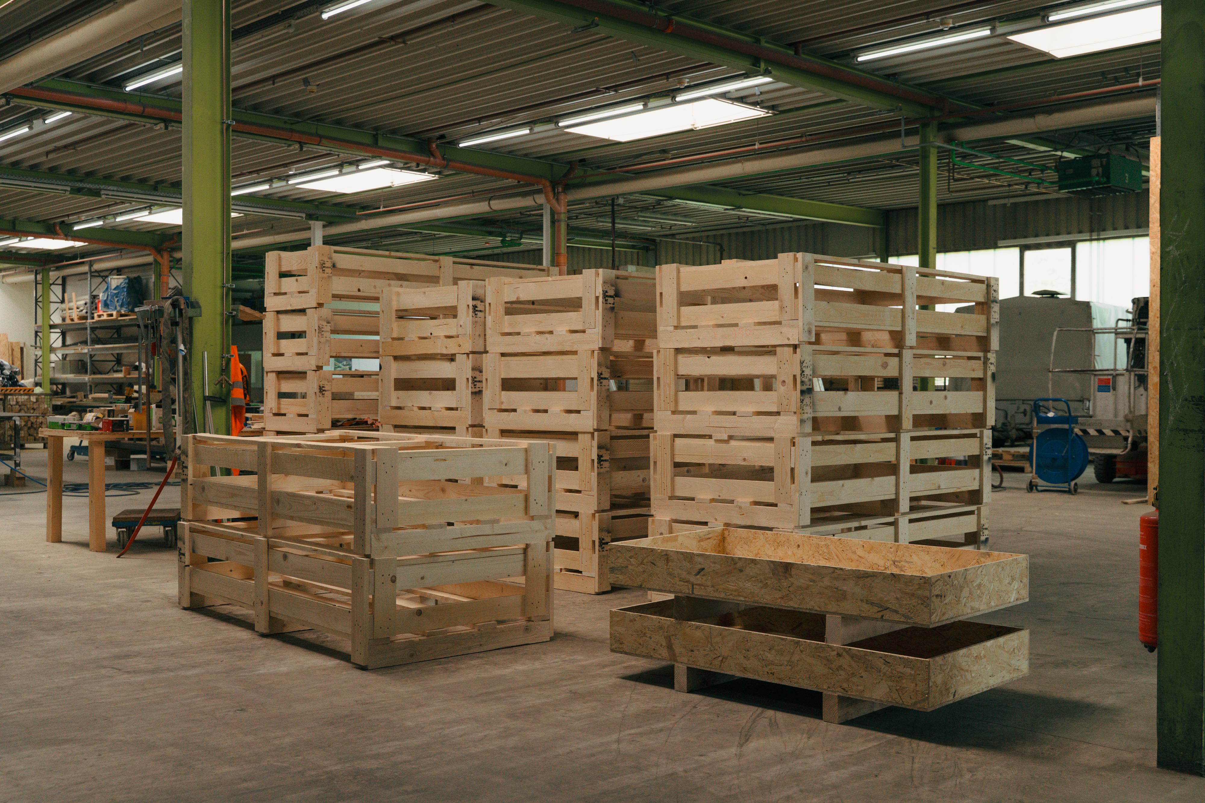 Holzpaletten und Kisten in einer Werkhalle.