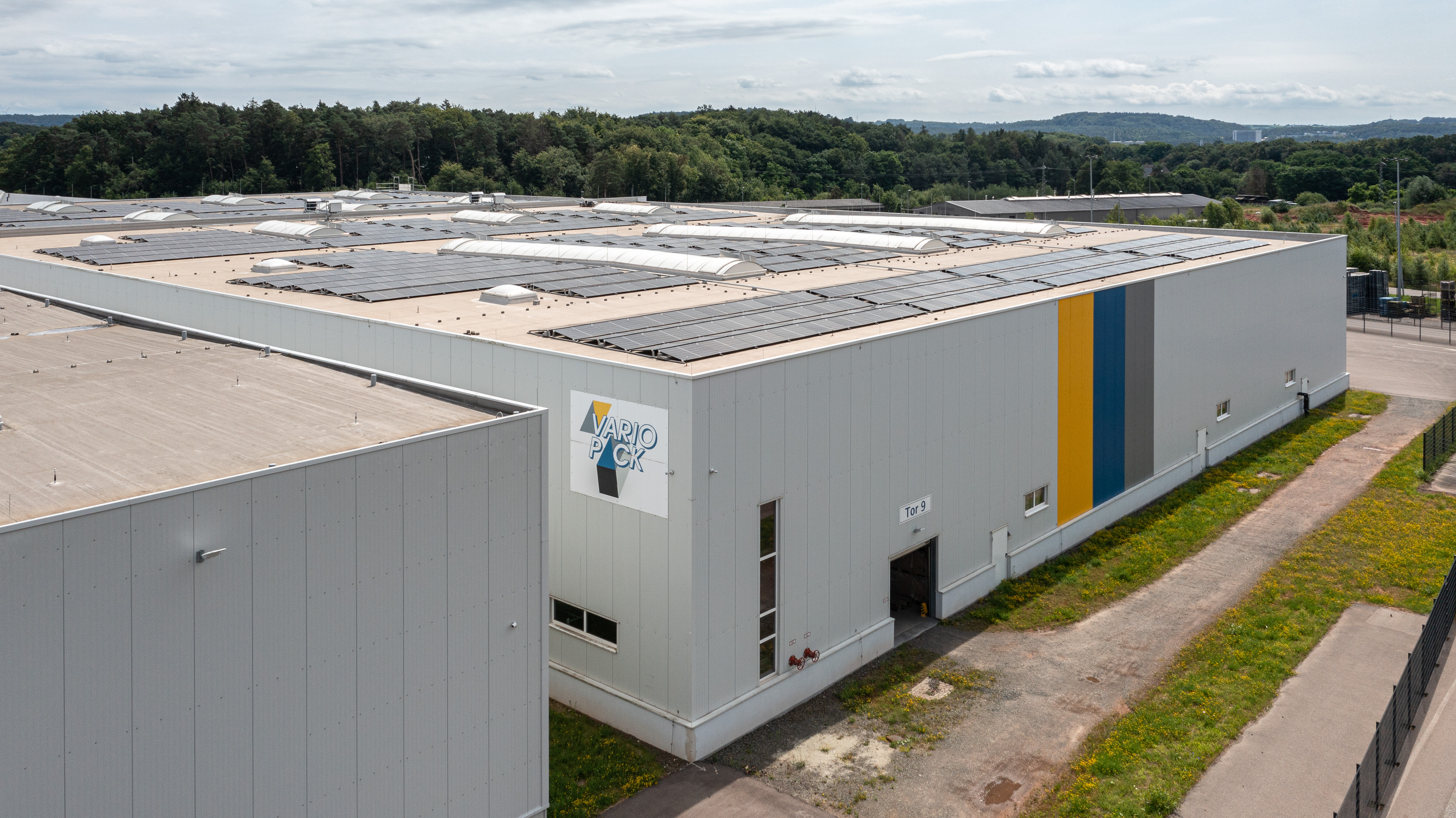 Außenansicht einer Variopack-Halle mit Logo und Solaranlage auf dem Dach.