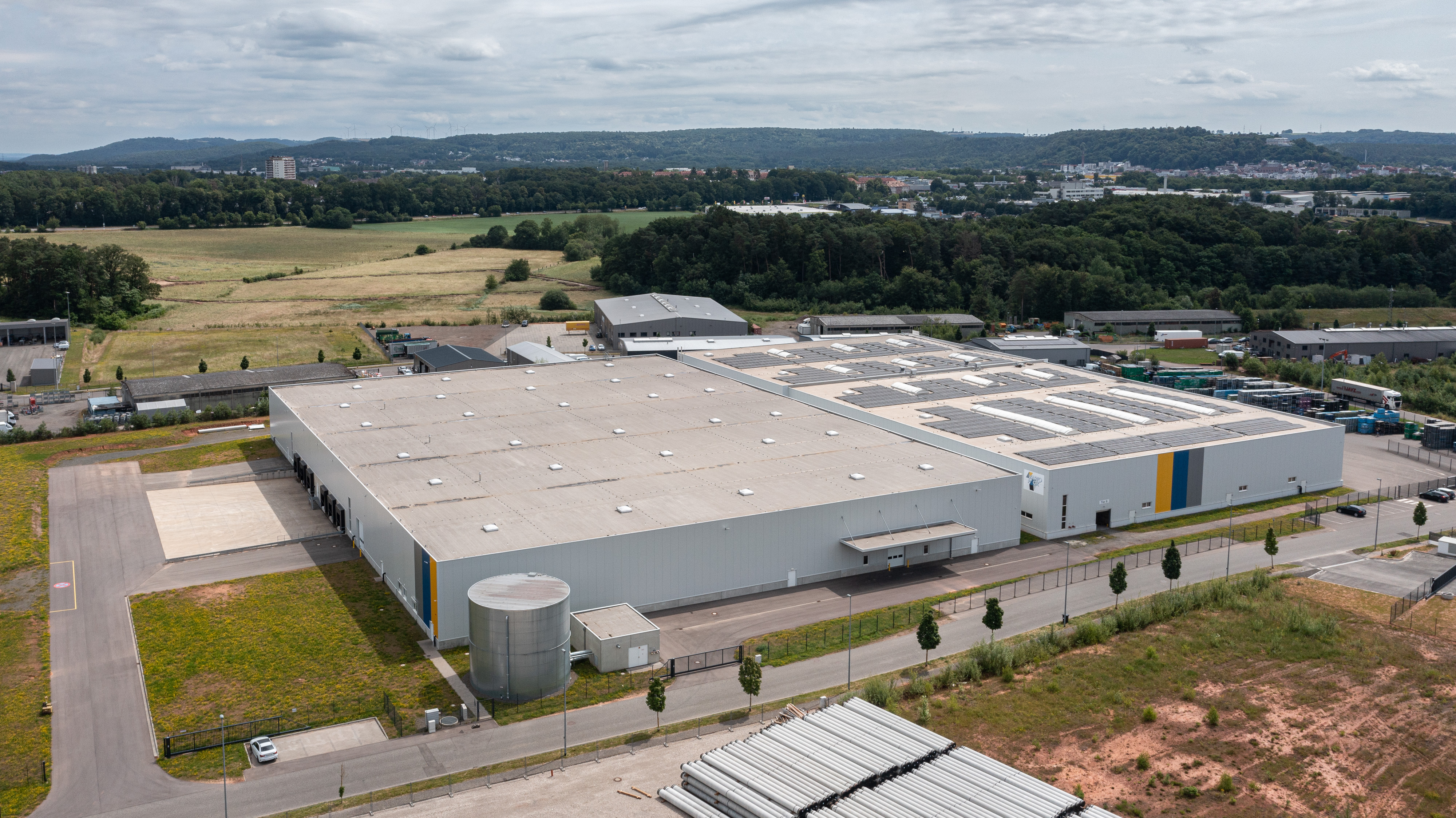Luftaufnahme des Werksgeländes mit umliegender Natur und Zufahrten.